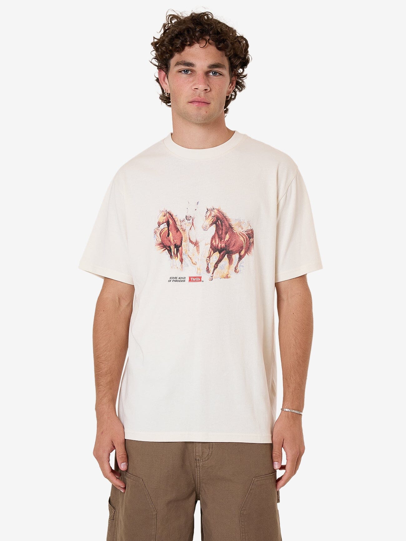 Male model wearing our Thrills Ruthless Frontier Merch Fit Tee in White standing against a plain studio background.