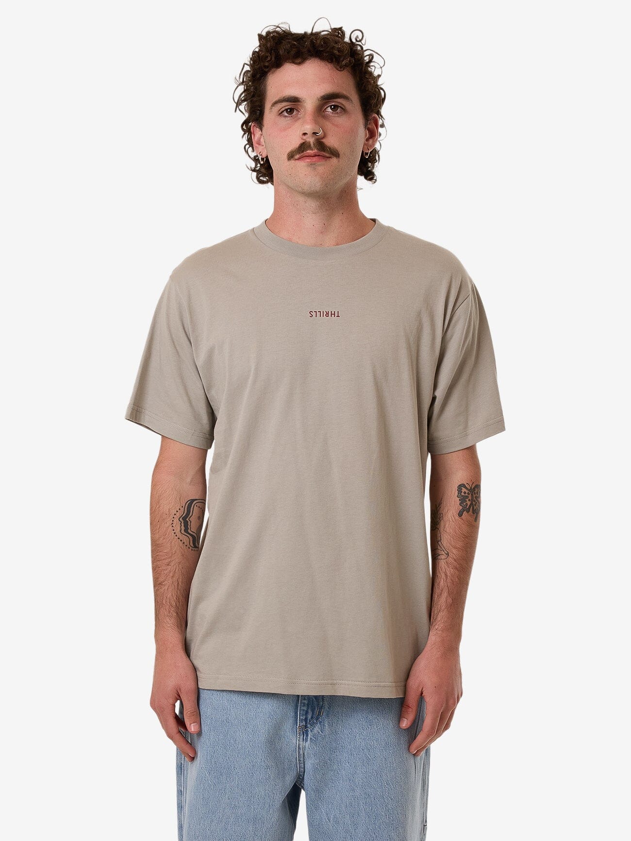 Male model wearing our Thrills Minimal Thrills Merch Fit Tee in Brown standing against a plain studio background.
