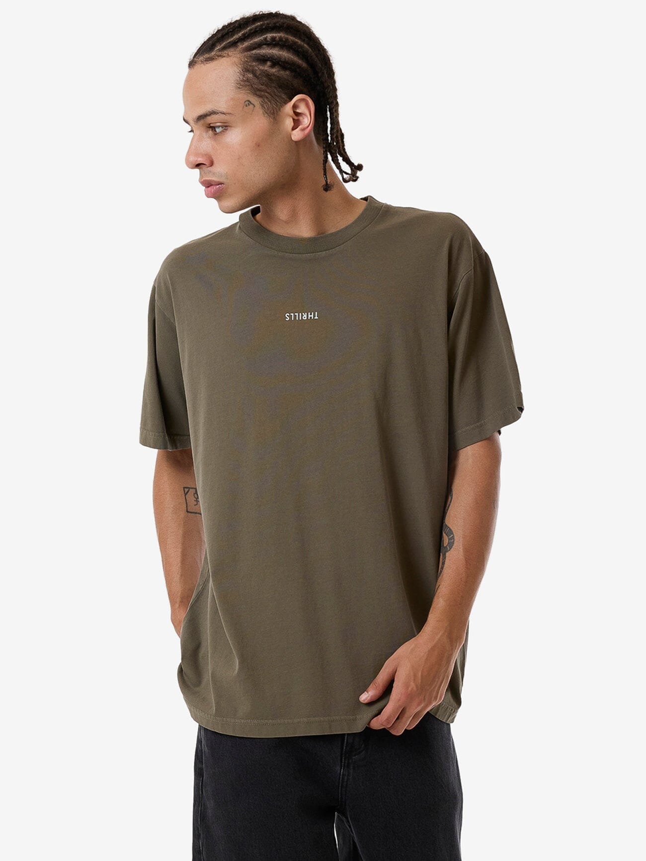 Male model wearing our Thrills Minimal Thrills Merch Fit Tee in Green standing against a plain studio background.