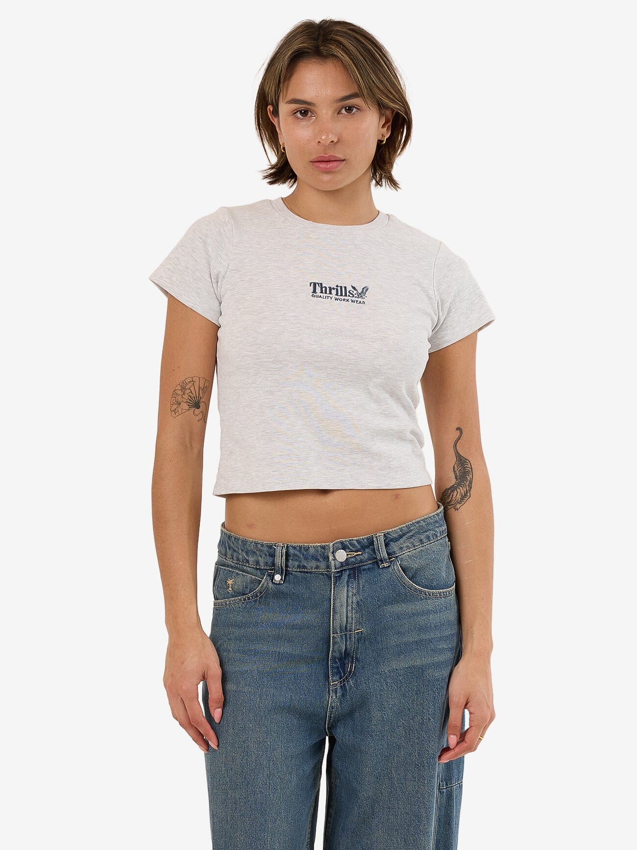 Female model wearing our Thrills Thrills Workwear Embro Mini Tee in White standing against a plain studio background.